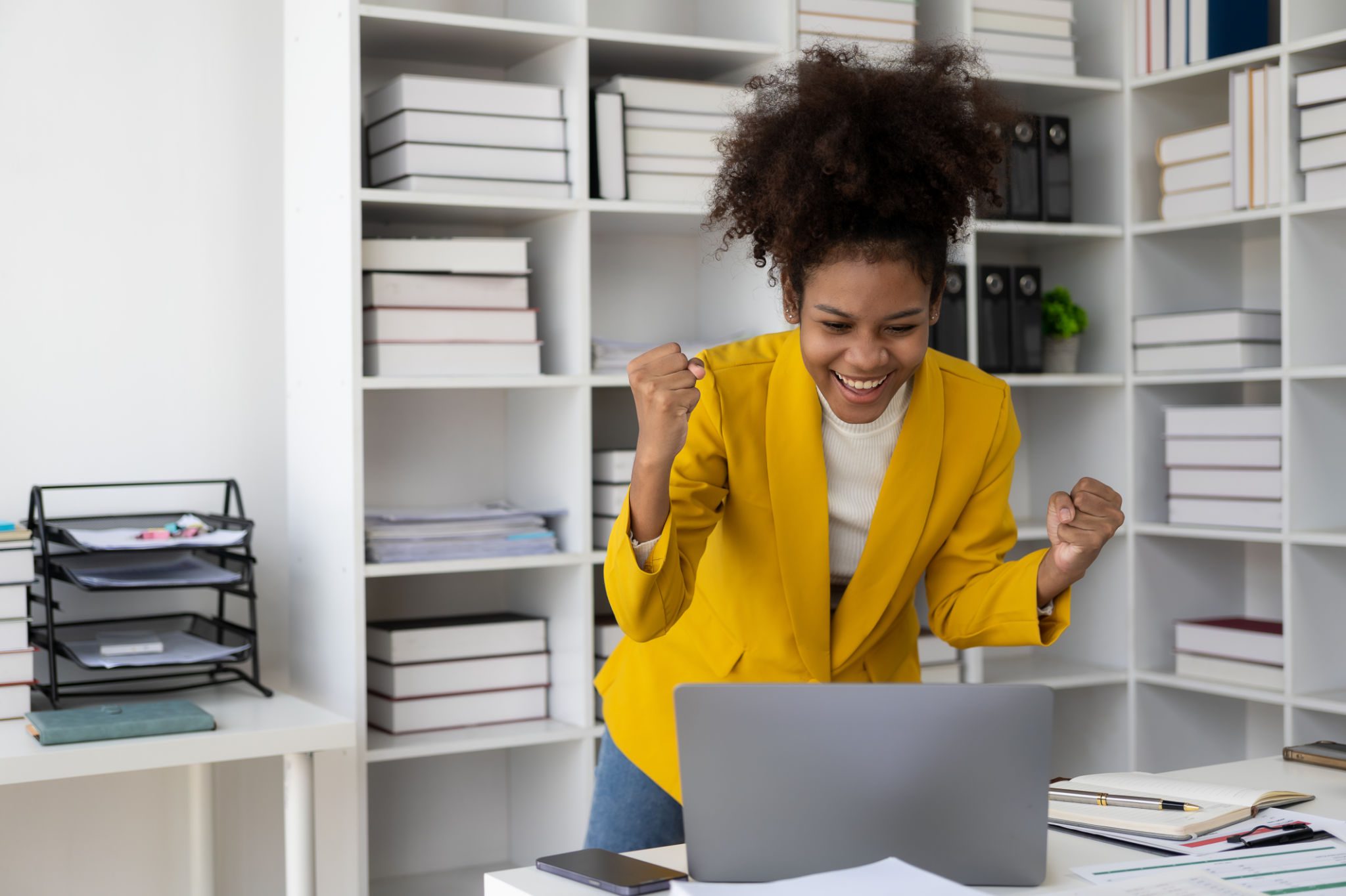 Woman celebrating success at her desk.