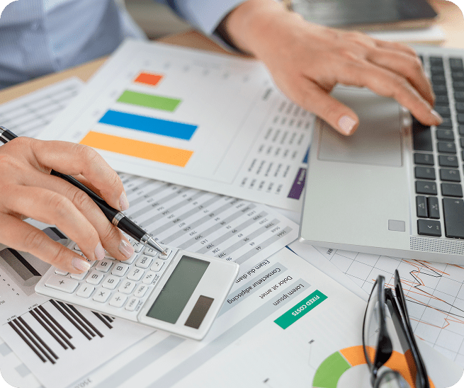 Hands using calculator and laptop on charts.
